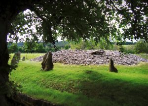 The prehistoric Clava Cairns burial chambers surrounded by standing stones and mature oak trees.