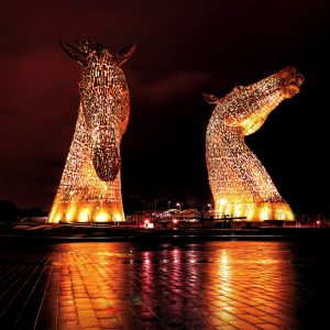 Scottish myths and legends. The Kelpies monument in Falkirk lit up in yellow.